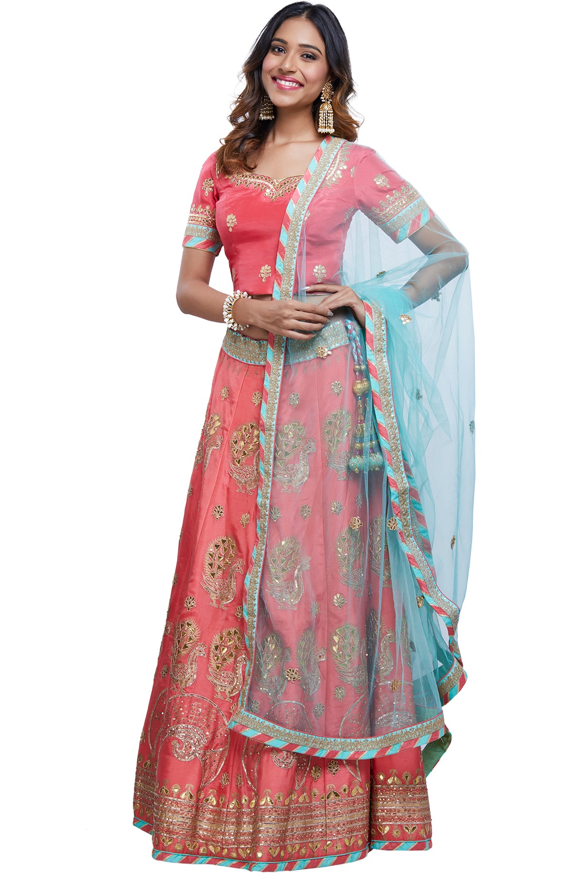 Step into the whimsical world of gorgeous fashion and meet some serious style goals with this stunning outfit. It comes with a pink silk choli, a sea green gota lehenga with peacock motifs and an embroidered net dupatta.