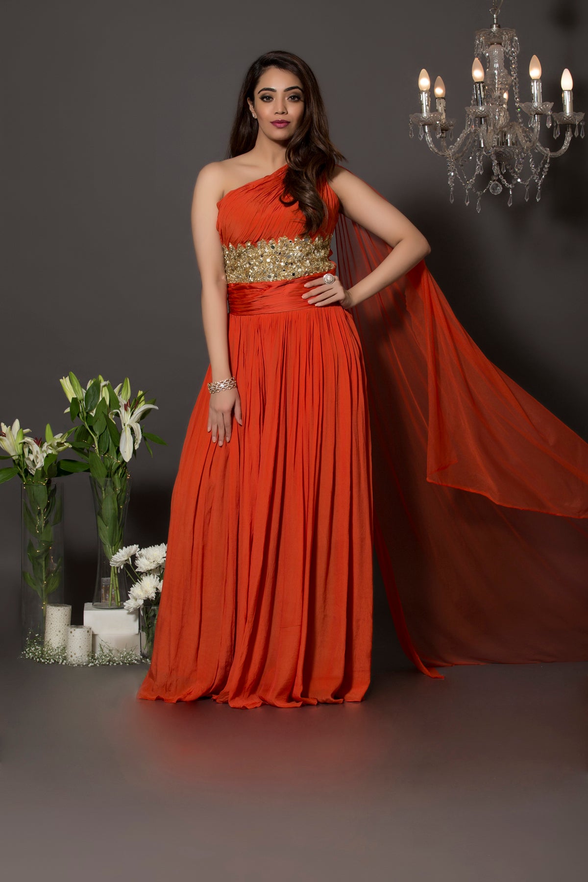 Pure crepe rust one shoulder jumpsuit with gathers on the body and sequins and mirror beautifully had crafted above the waist. This piece comes with a soft net veil attached at the shoulder.