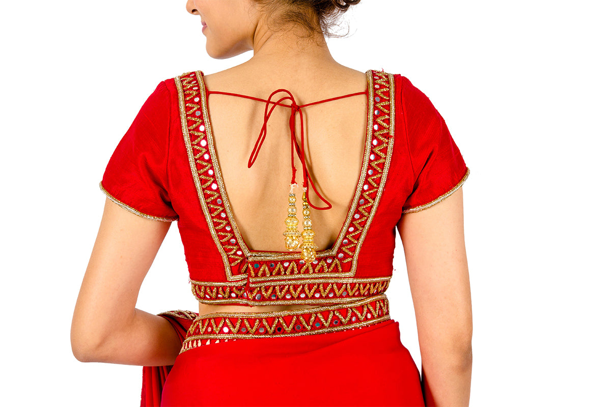 Red Raw Silk Blouse With Mirror Work On Front And A Deep Back is not the usual blouse you'd pair with a saree. This intrinsically designed work has a latkan at the back. 