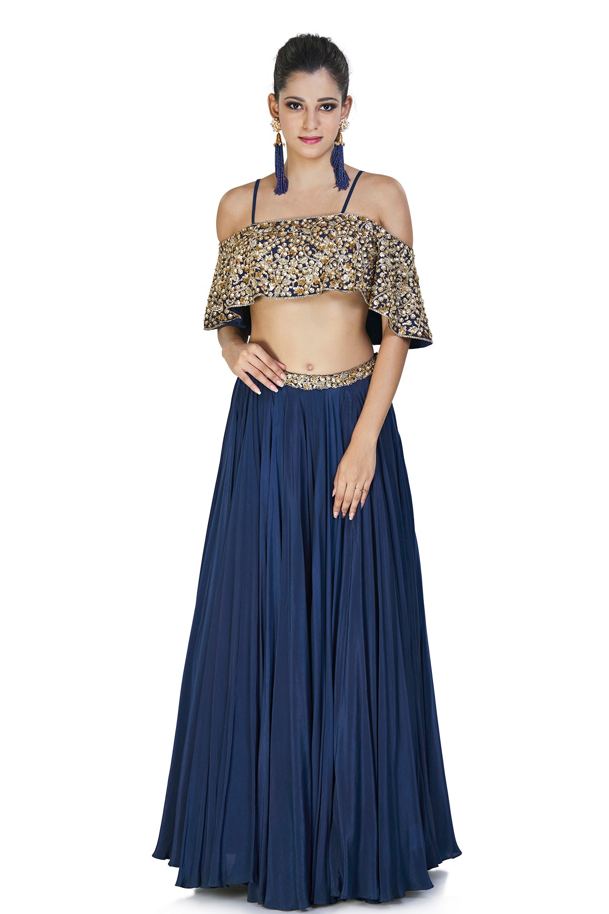 This graceful navy blue ethnic ensemble is finely crafted and comes with a crepe silk skirt with an embellished belly and an off shoulder cape style blouse with sequins and spaghetti straps.