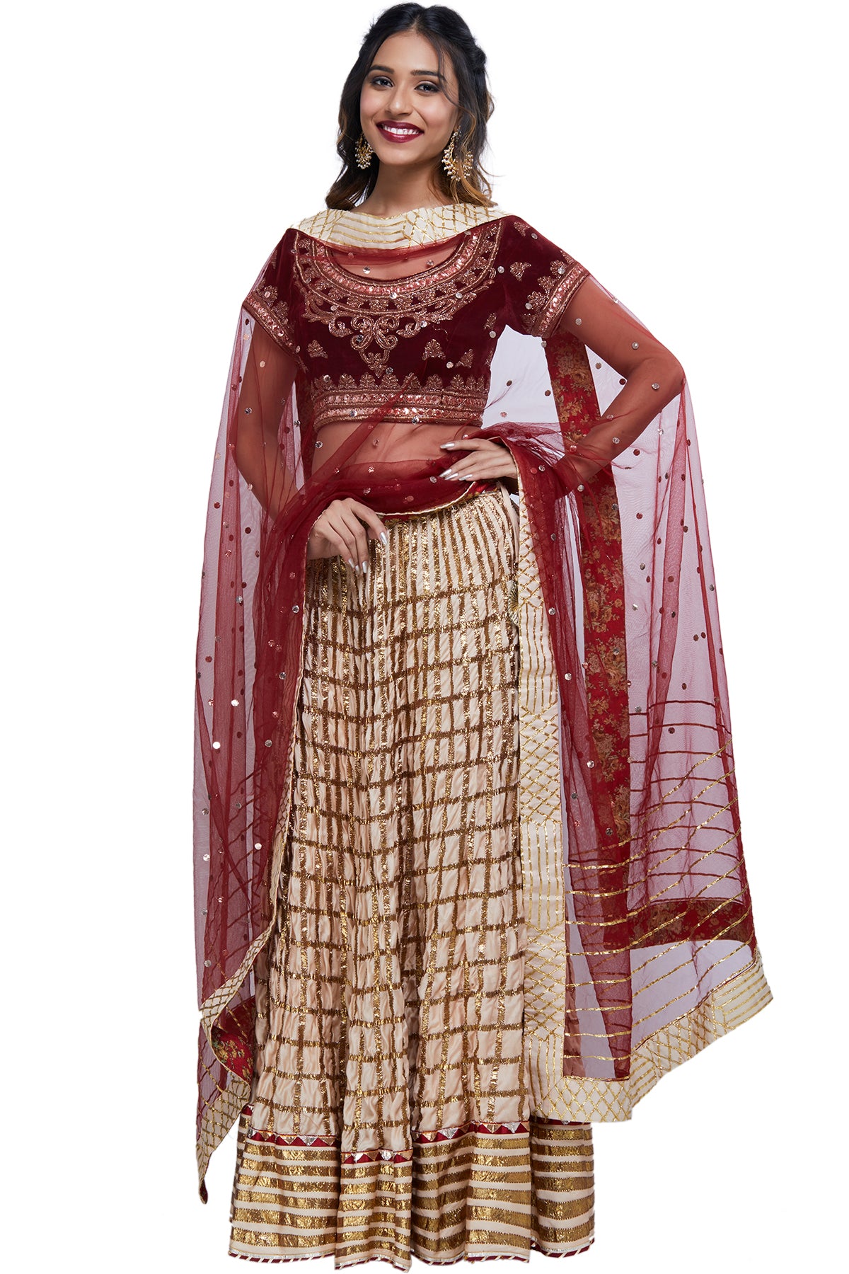 It's your big day and here's all you need to slay. Get your hands on this outfit with its maroon velvet blouse embroidered in zardosi and baadla work over a cream lehenga embroidered in geometric patterns finished with Hyderabadi gota.